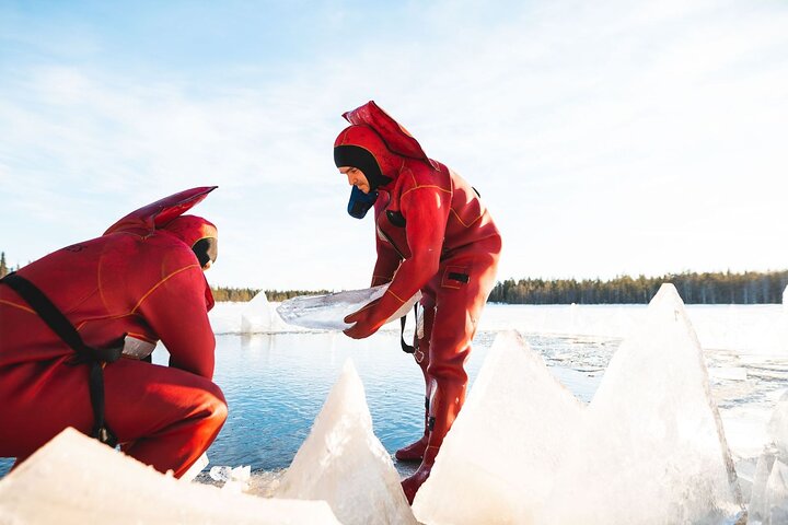 Participants in floating suits among broken lake ice