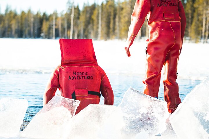Participant wearing a red thermal floating suit beside the frozen lake