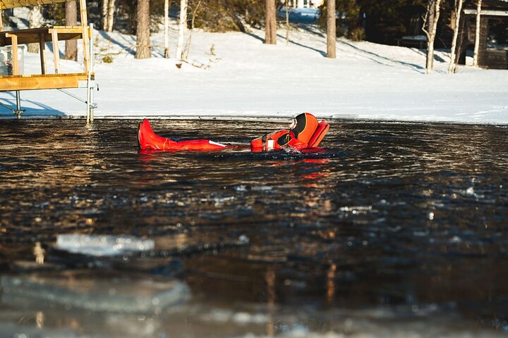 Visitor floating in open water among lake ice